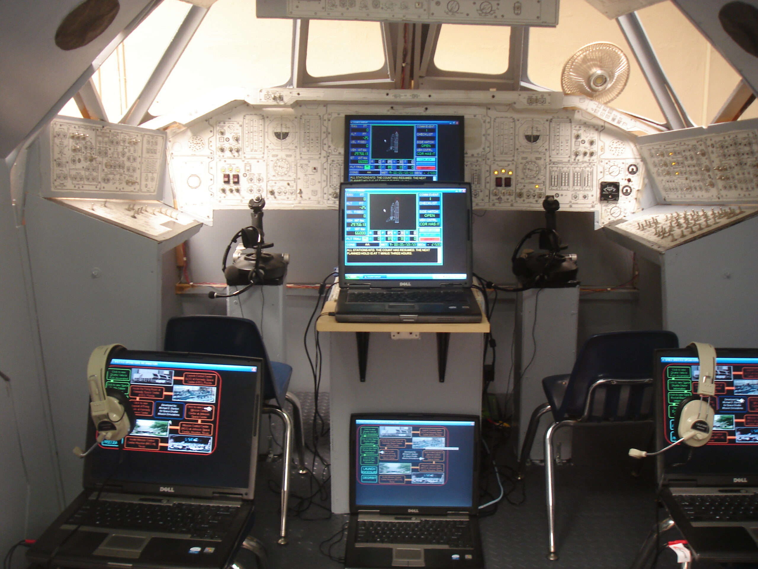 photo showing 4 laptop computers in the space shuttle simulator, arranged for command shifts